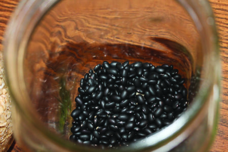 top down view of a glass mason jar partially filled with dried black beans.